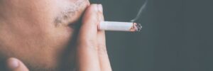 Man smoking a cigarette which could increase his risk of gum disease