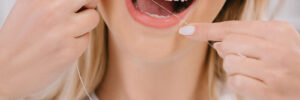 cropped view of woman flossing teeth with dental floss