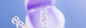 A person holding a set of clear braces on a blue background.