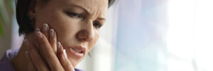 Woman in pain holding the side of her face from an infected tooth