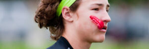 Young athlete playing 7 on 7 football with gloves and headband with mouthpiece in mouth.